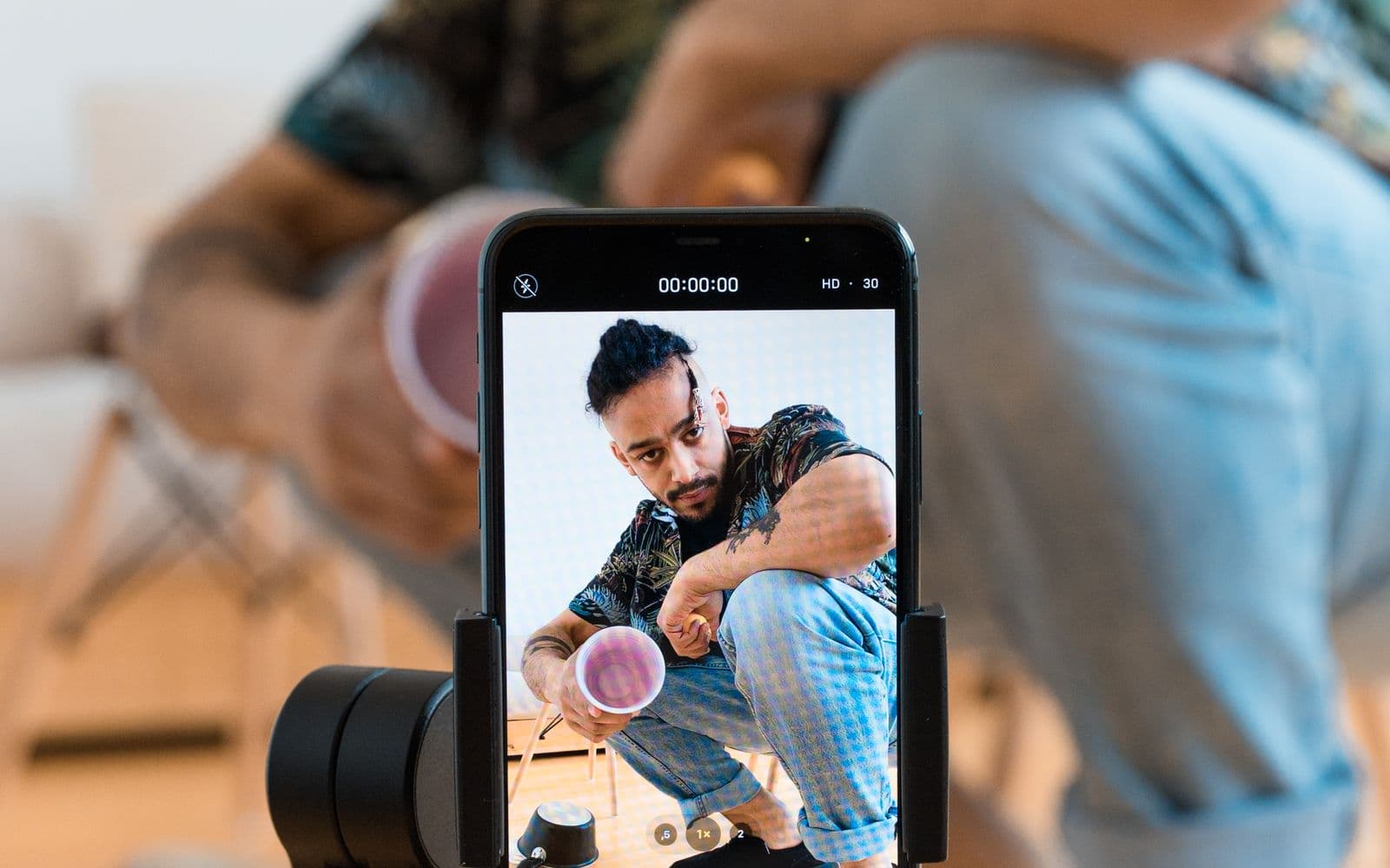 A phone on a gimbal recording a man in a patterned shirt, seen on the phone screen