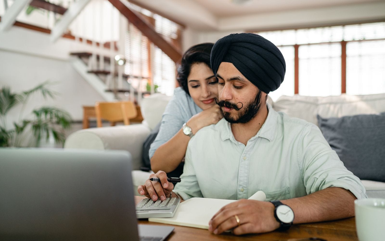A couple working out their budget with a calculator and notebook at home