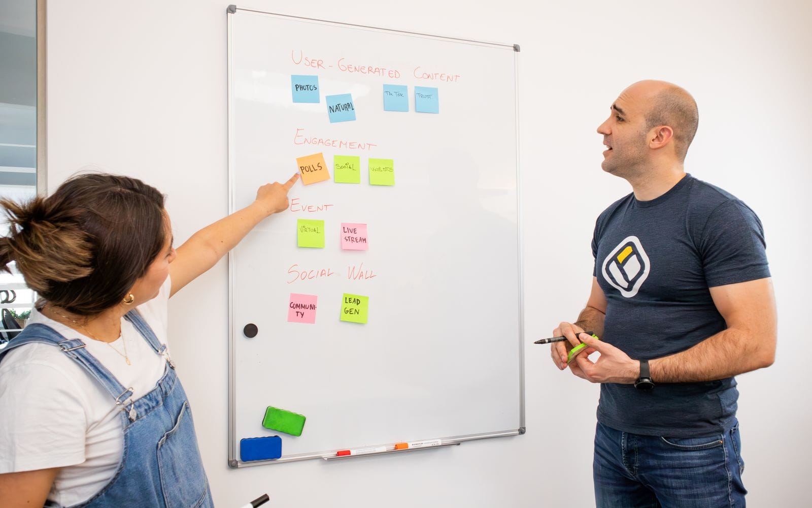 Two colleagues planning with sticky notes on a whiteboard