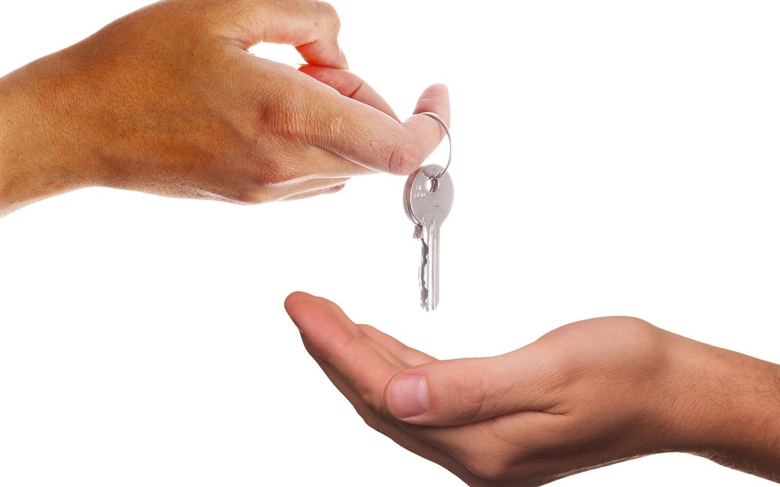 One hand dropping a house key into another open hand