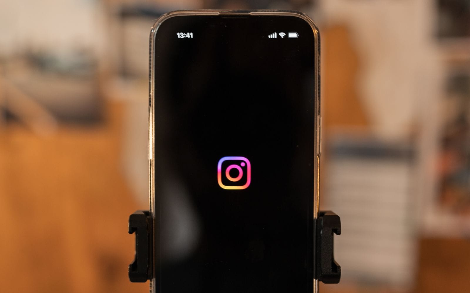 A smartphone showing the Instagram logo, held upright in a tripod clamp