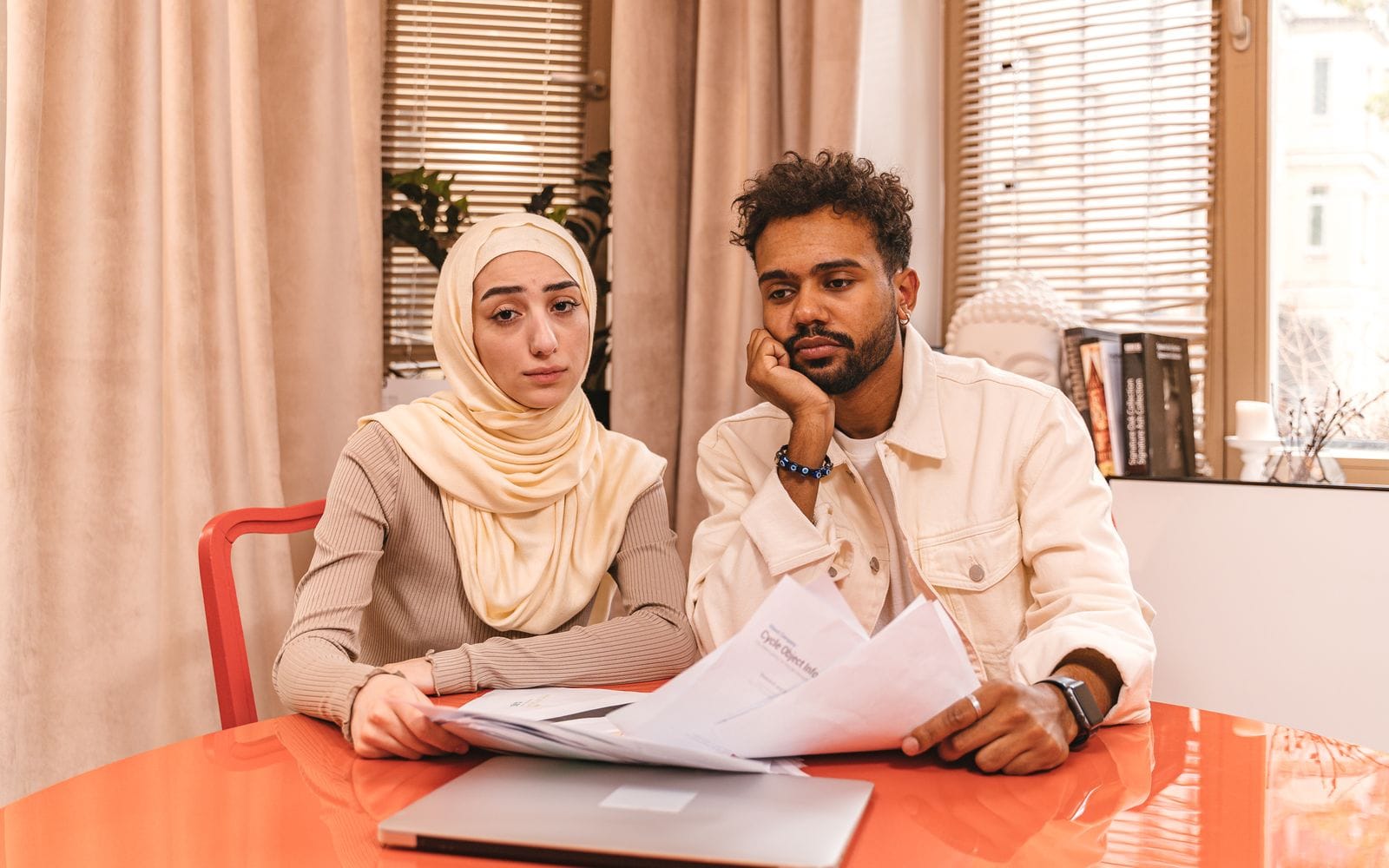 A young couple sitting at a table going through printed property documents