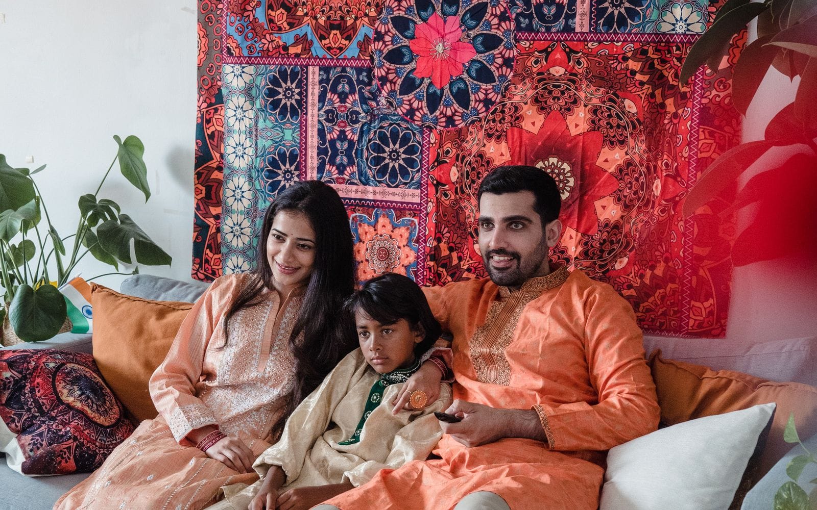 A smiling family of three sitting on a sofa in a colourful living room
