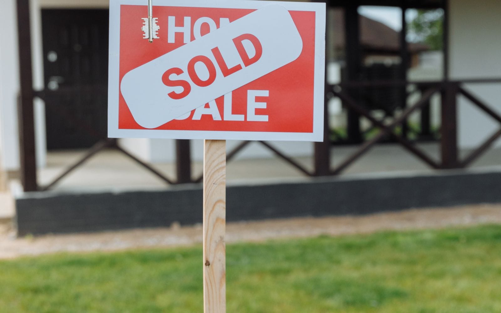 A red and white sold sign on a post in front of a house