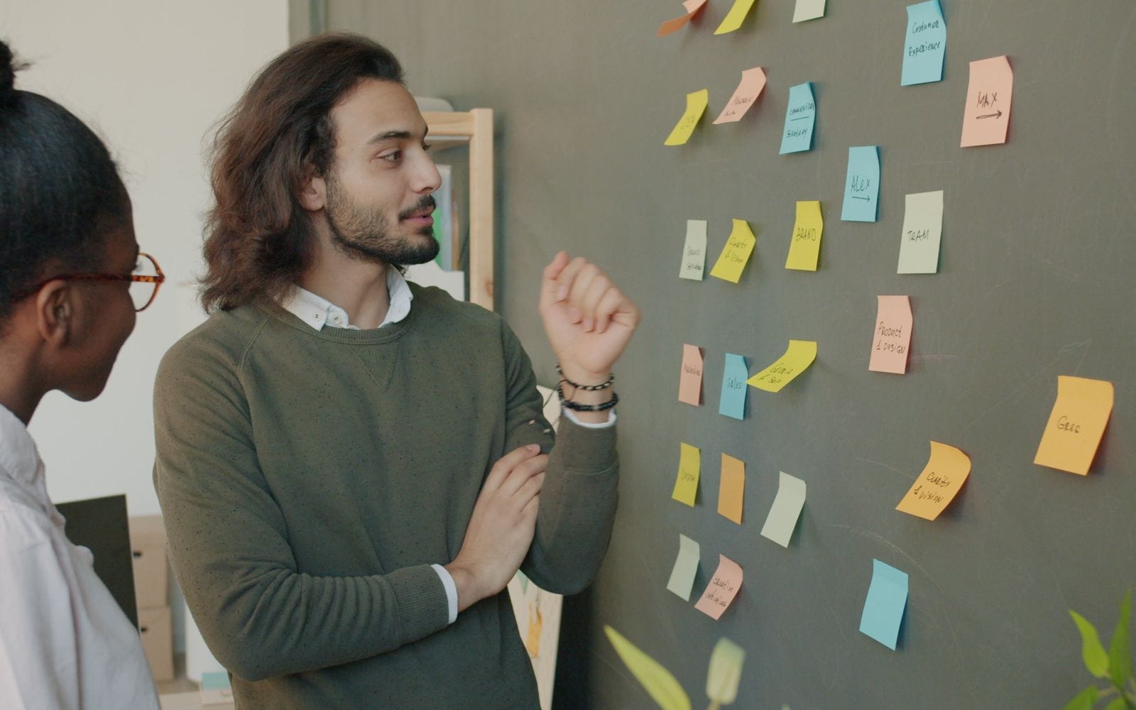 Three colleagues discussing ideas in front of a wall of sticky notes