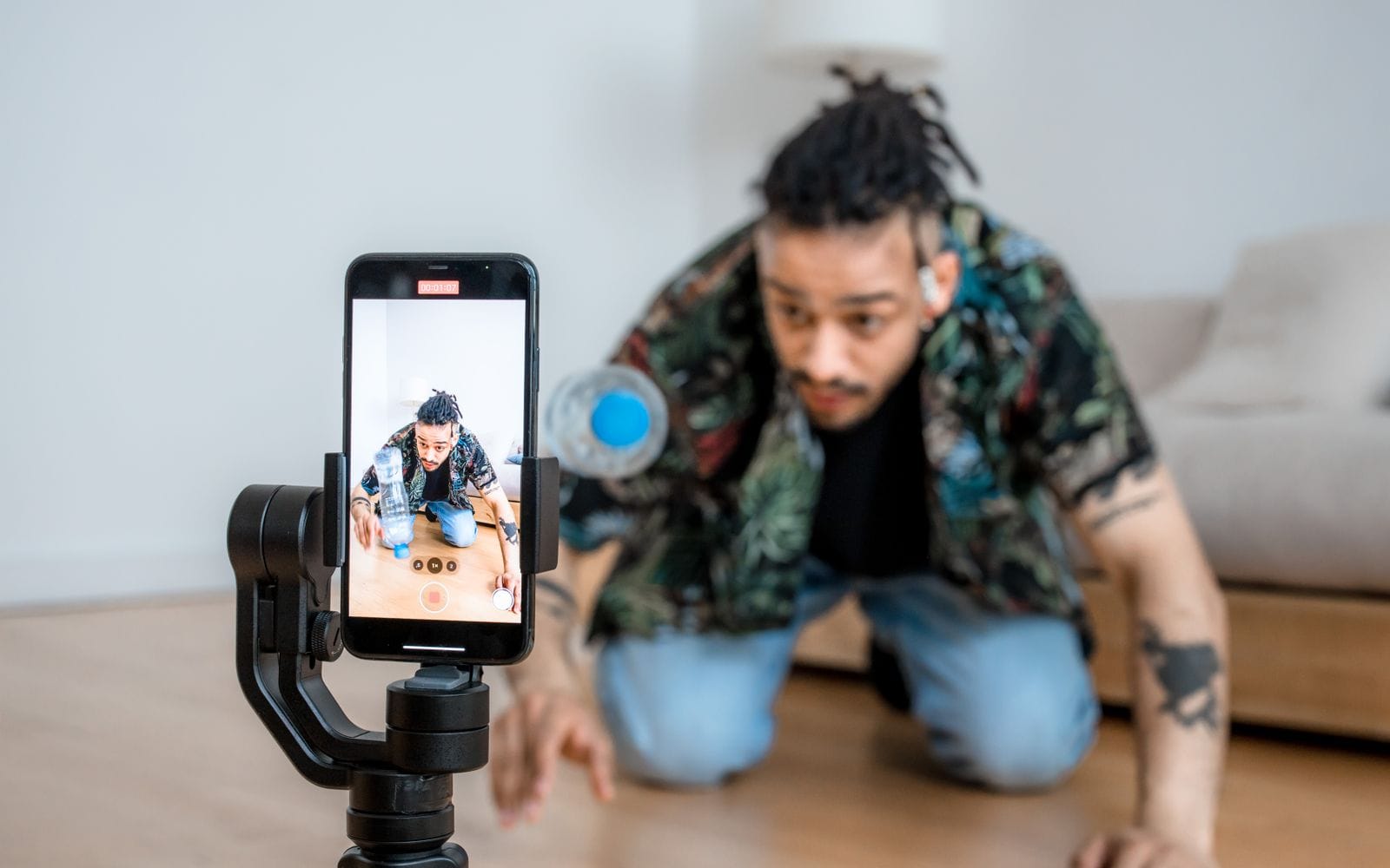 A man setting up a smartphone on a gimbal to record himself indoors