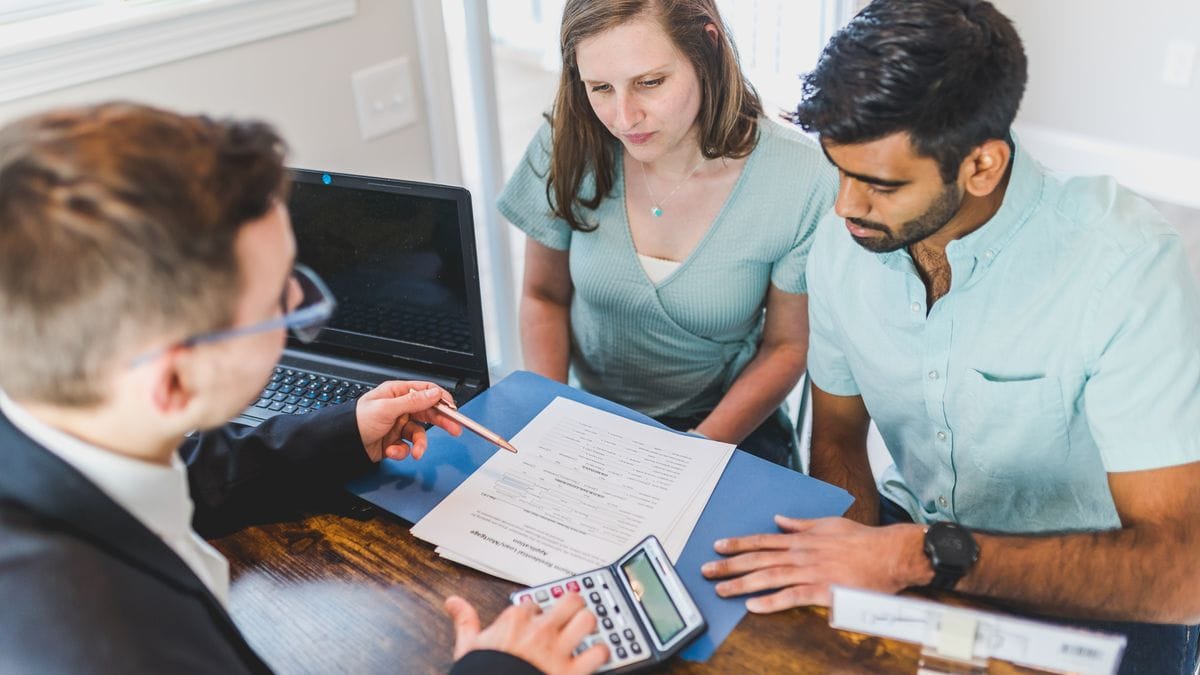 Property agent going through paperwork with a couple at a table