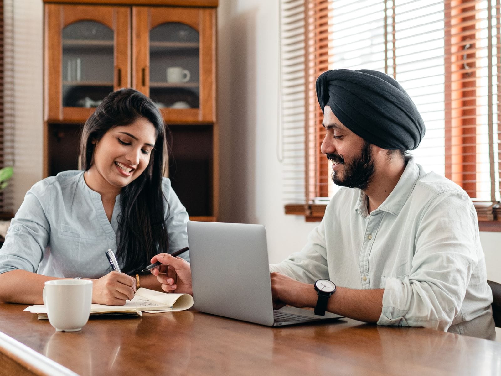 Two people planning a marketing campaign together at a laptop, one taking notes