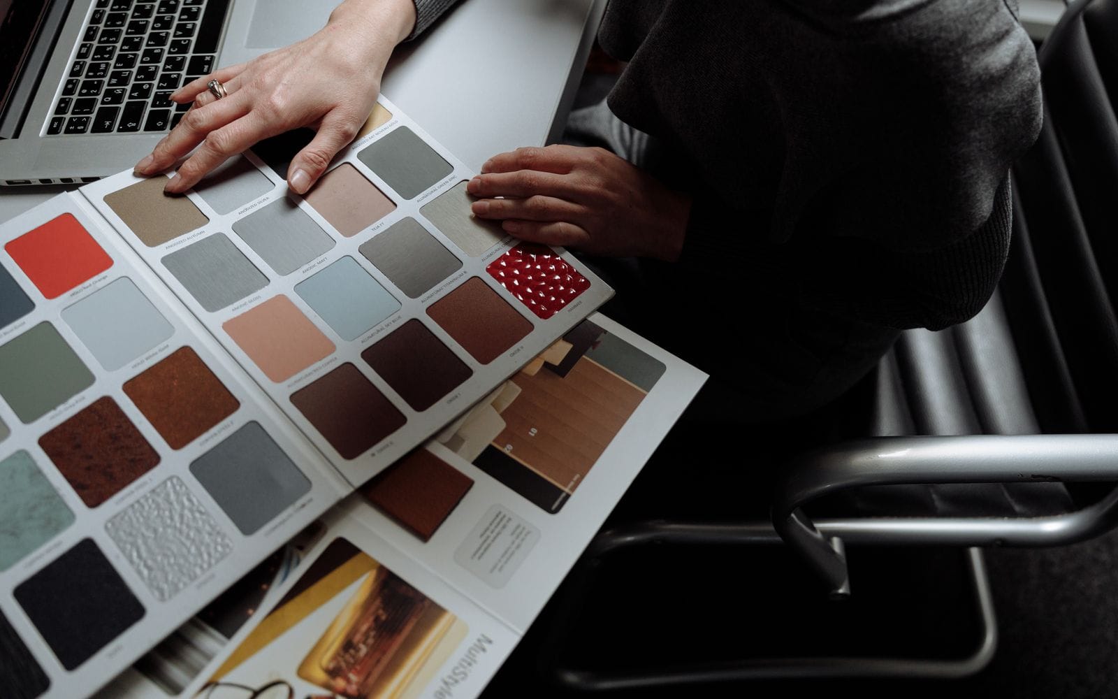 A designer at a laptop comparing colour and material swatch cards