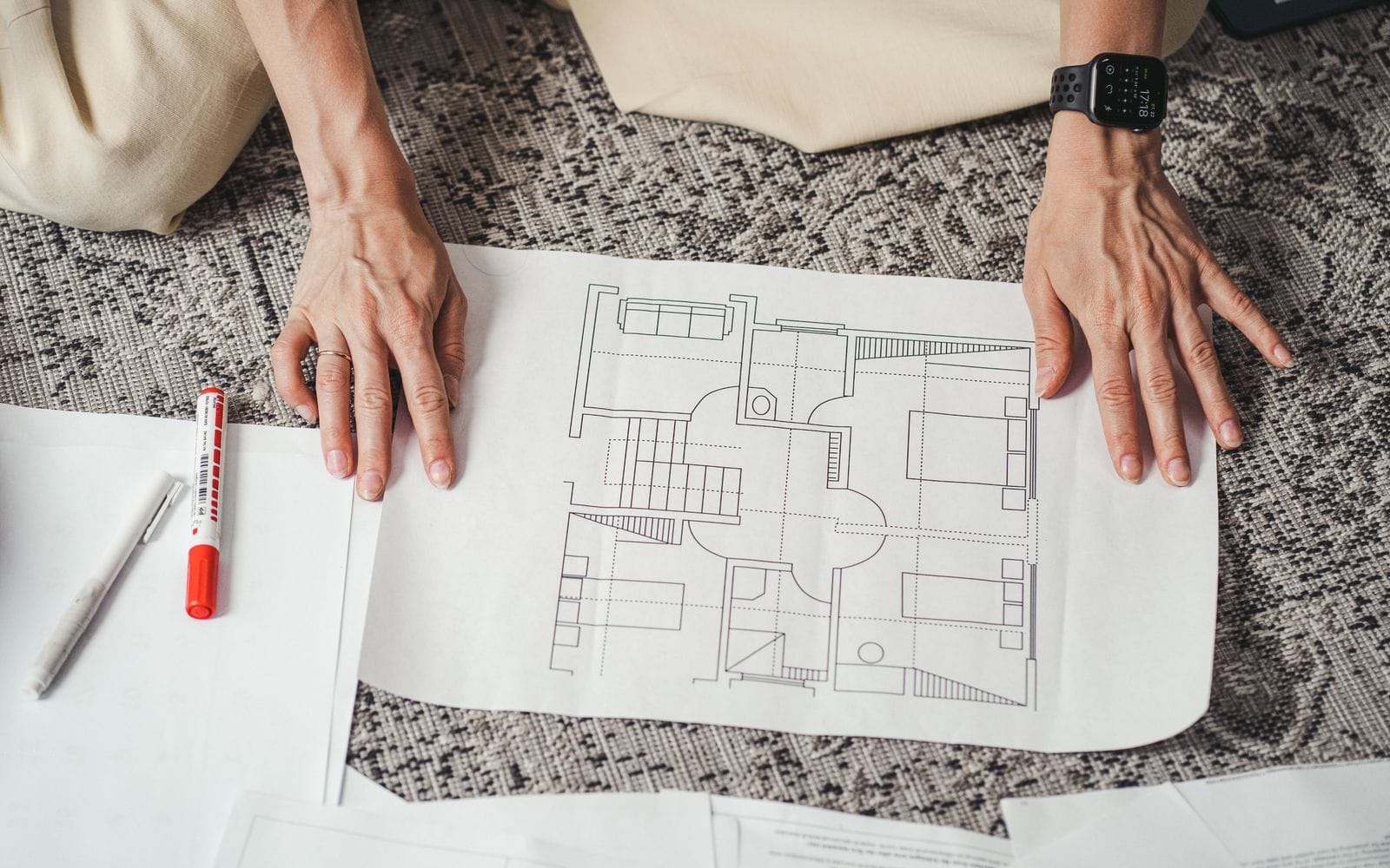 Hands resting on a printed architectural floor plan with a pen beside it