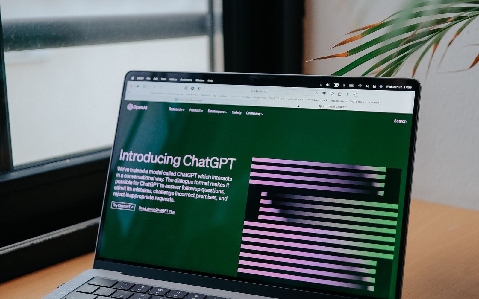 A laptop on a desk showing the ChatGPT introduction page on a green screen