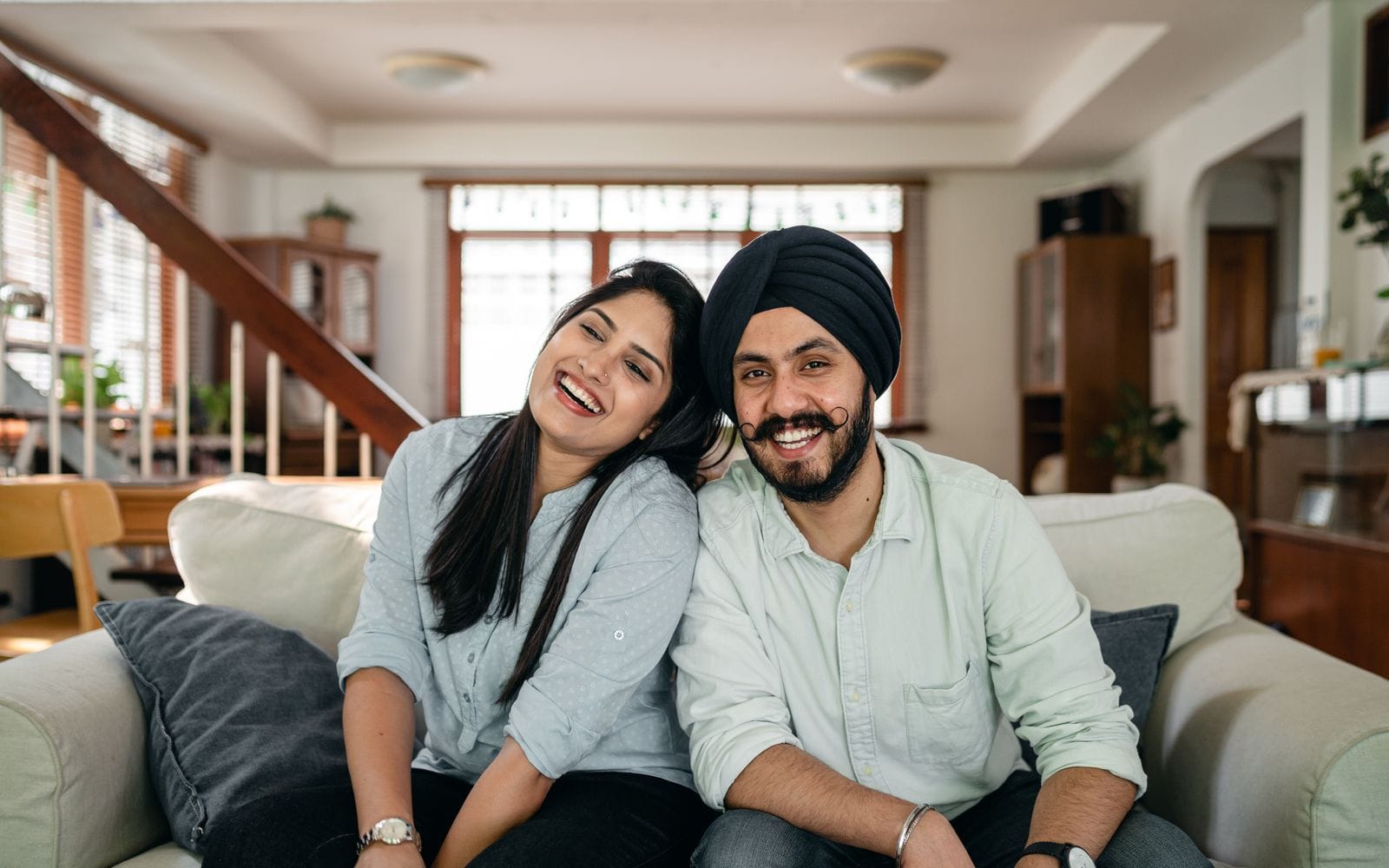 A young couple laughing together on a sofa at home