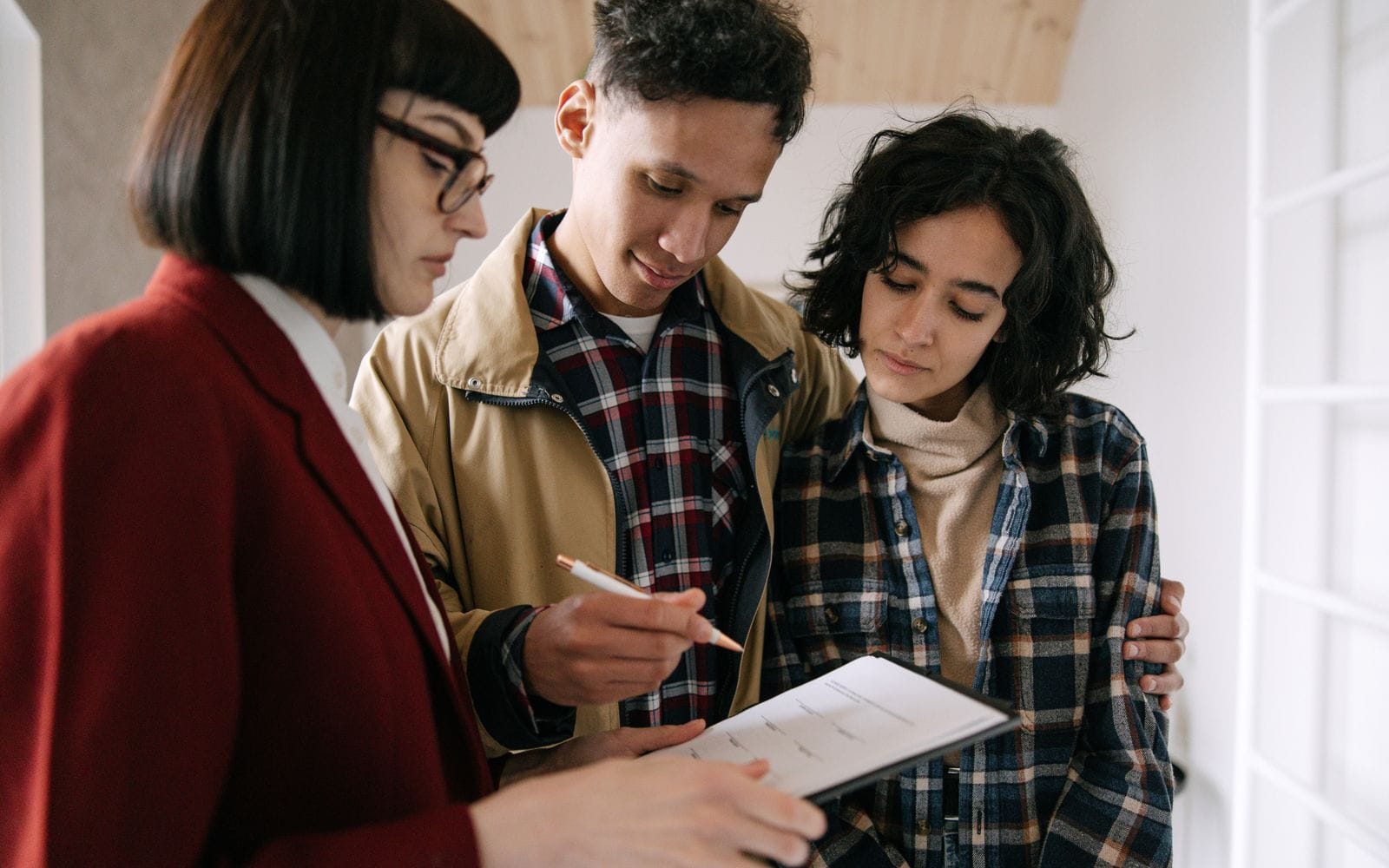 A property advisor going through papers with a young couple inside an apartment
