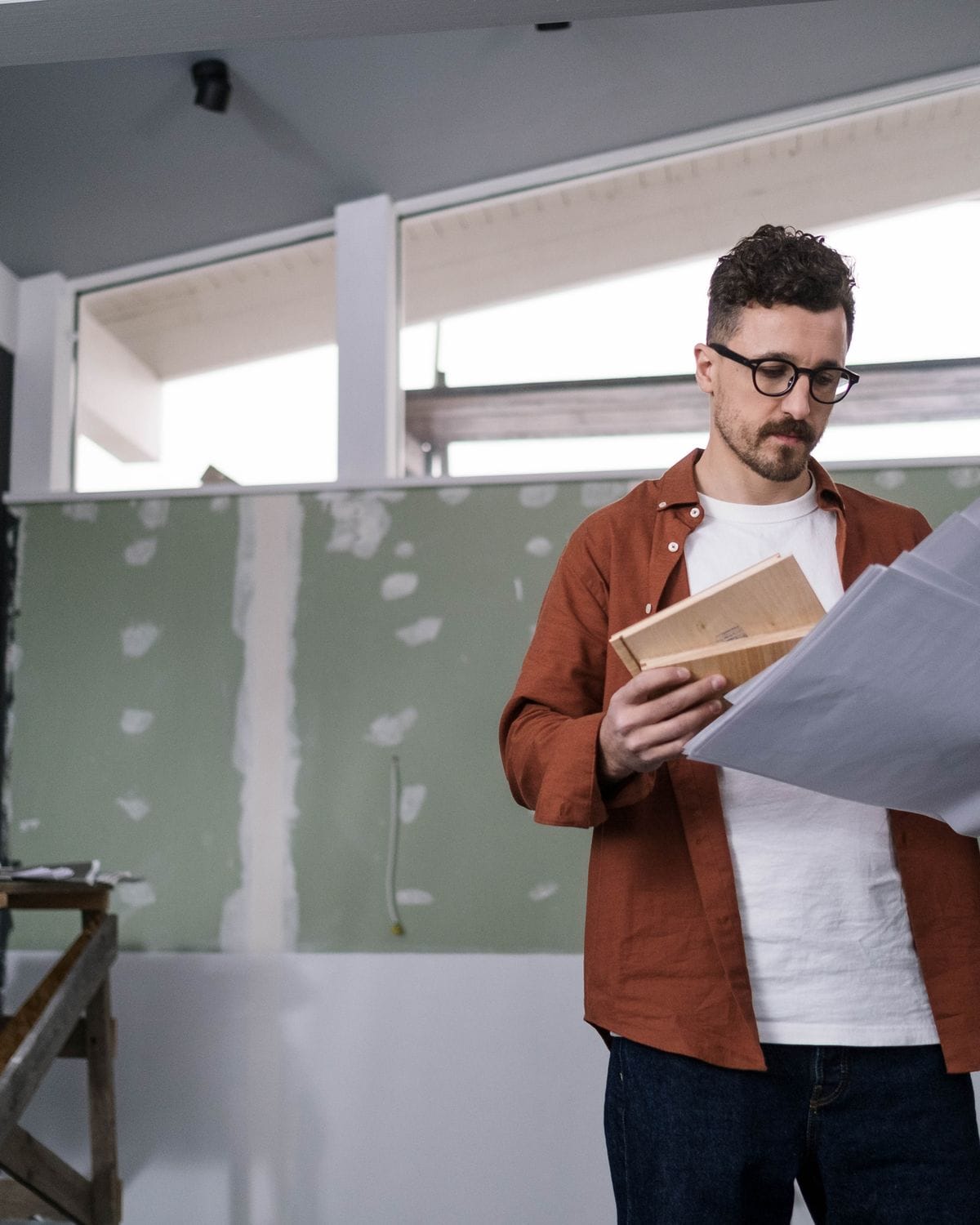 Man reading building plans inside a flat that is still under construction