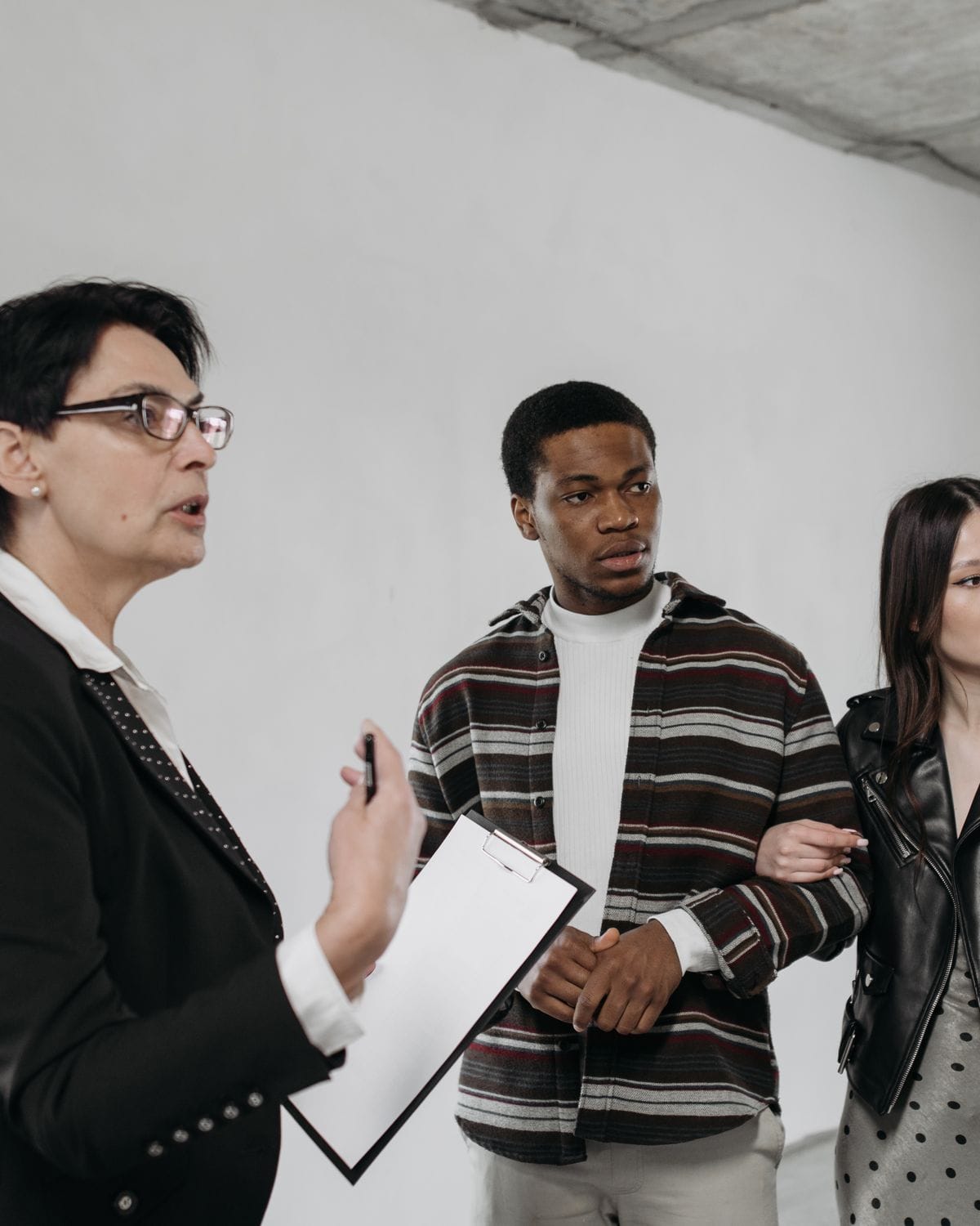Sales executive with a clipboard showing a young couple around an unfinished apartment
