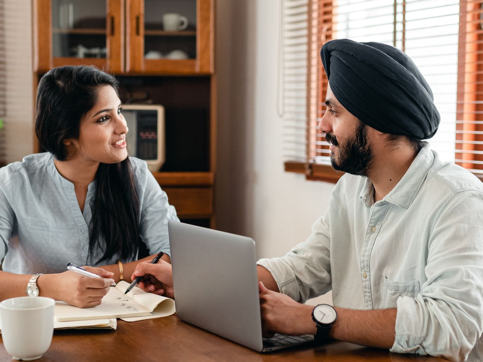 A man and a woman going through a marketing review at a table with a laptop and notebook