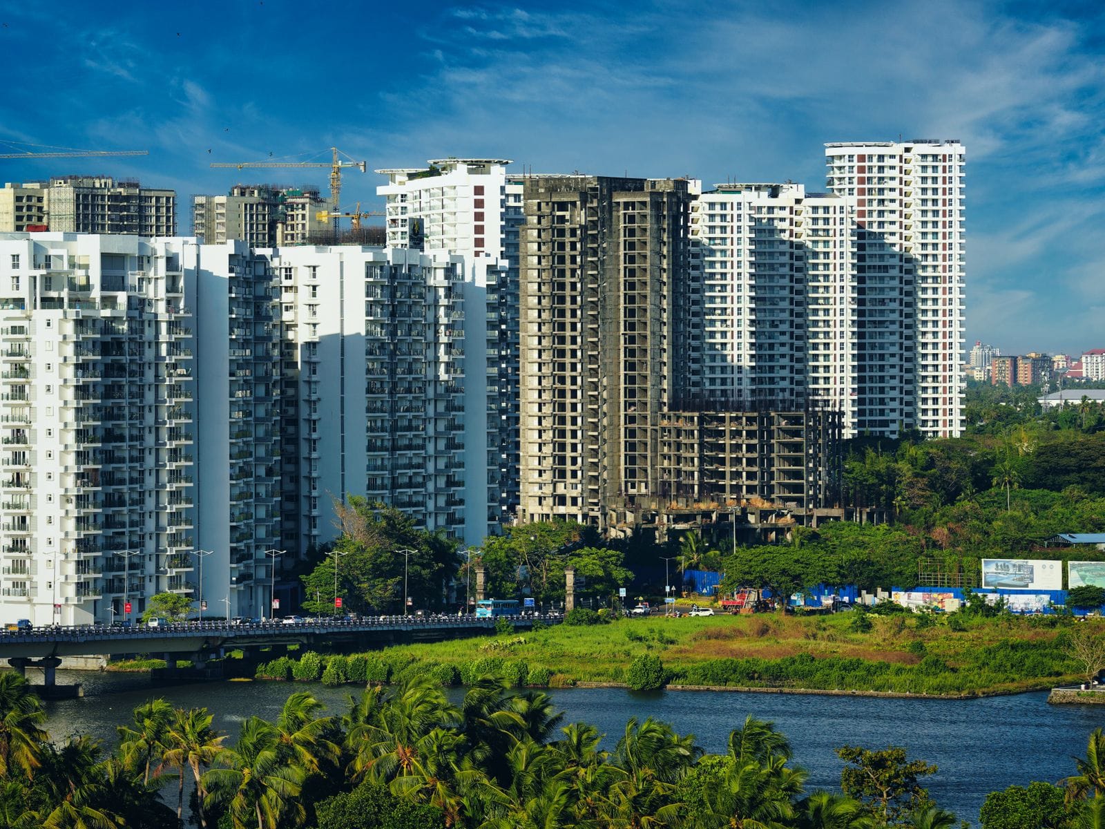 Tall residential towers beside a lake, with green trees in the foreground