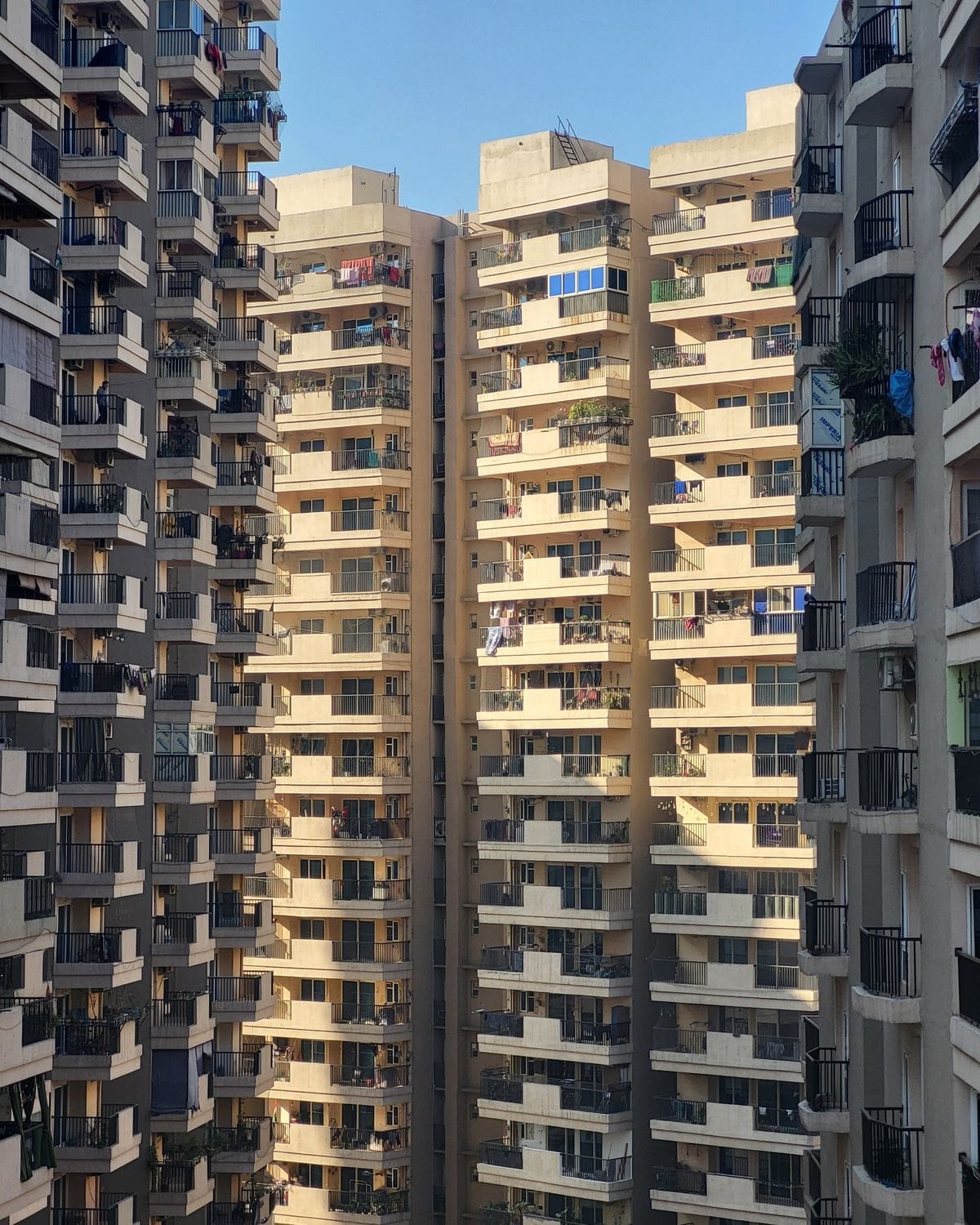 Tall apartment buildings with rows of balconies lit by the evening sun