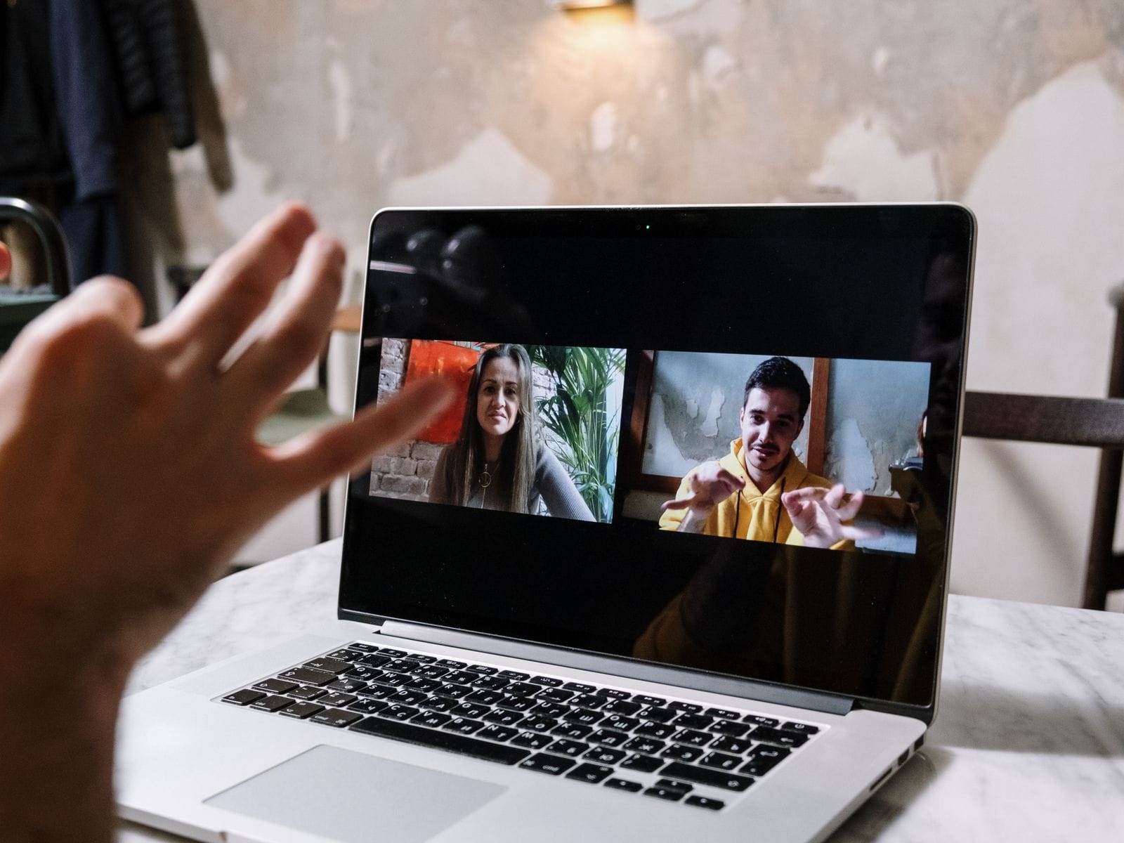 Person on a video call with two people on a laptop screen