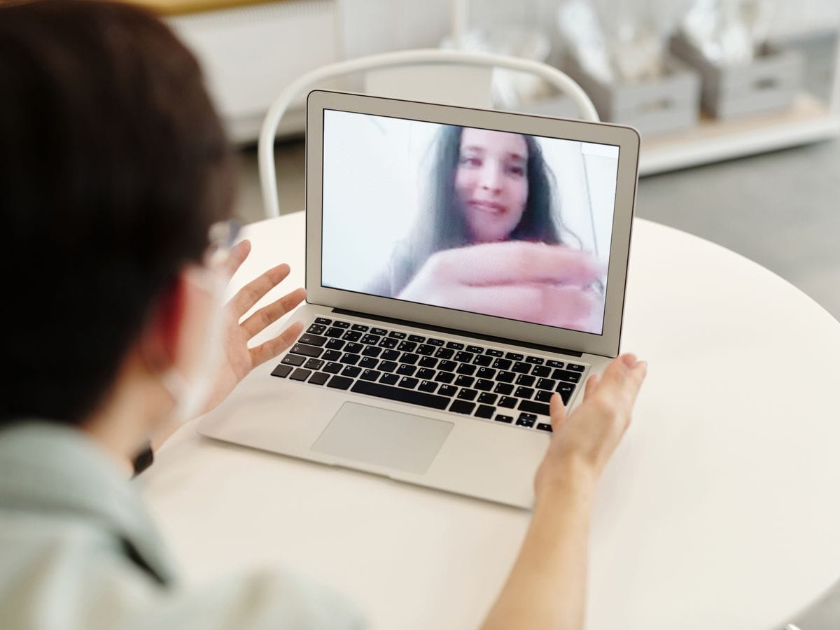 Person on a laptop video call with a smiling woman on screen